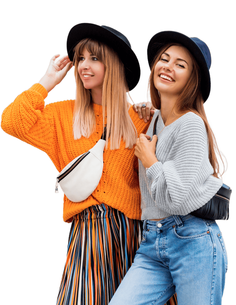 Two women smiling while thrifting at Talize, wearing hats and secondhand outfits